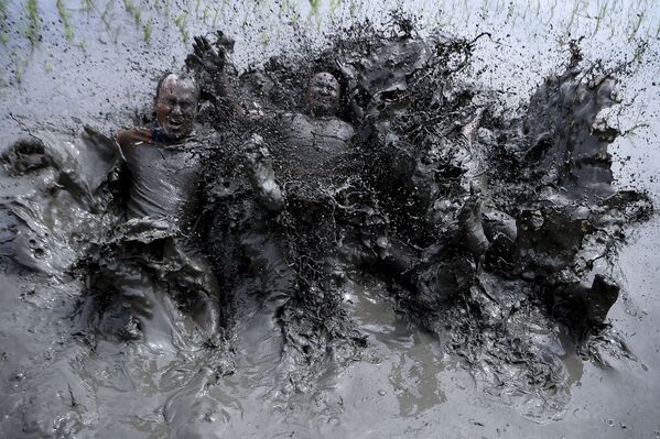 Agricultores cobertos de lama se divertem em campo de arroz durante o Dia Nacional do Arroz, na aldeia de Tokha, arredores de Katmandu, Nepal, 29 de junho de 2021 - Sputnik Brasil