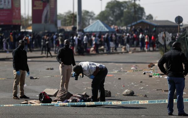 Policiais inspecionam o corpo de uma vítima em meio aos protestos em Katlehong, África do Sul, 12 de julho de 2021 - Sputnik Brasil