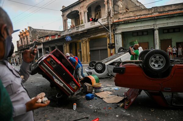 Viaturas policias e veículos civis foram vistos capotados na rua durante a manifestação contra o presidente cubano Miguel Diaz-Canel em Havana, no domingo (11) - Sputnik Brasil
