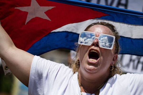 Uma manifestante segura a bandeira cubana enquanto protestava em frente à Casa Branca, em Washington, nos EUA, na segunda-feira (12) - Sputnik Brasil