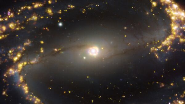 Galáxia NGC 1300 próxima à Via Láctea. NGC 1300 é uma galáxia espiral, com uma barra de estrelas e gás em seu centro, localizada a aproximadamente 61 milhões de anos-luz da Terra na constelação Eridanus. A imagem é uma combinação de observações realizadas em diferentes comprimentos de onda de luz para mapear populações estelares e gás quente. Os brilhos dourados correspondem principalmente a nuvens de hidrogênio ionizado, oxigênio e gás sulfúrico, marcando a presença de estrelas recém-nascidas, enquanto as regiões azuis no fundo revelam a distribuição de estrelas ligeiramente mais velhas - Sputnik Brasil