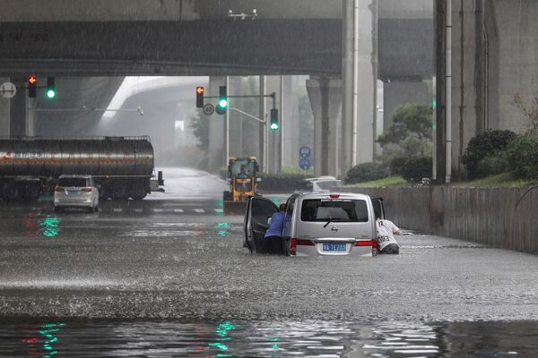 Pessoas empurram uma furgoneta durante as chuvas fortes que atingiram a cidade de Zhengzhou, China, 20 de julho de 2021 - Sputnik Brasil