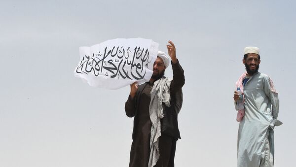 Homem no lado afegão da fronteira segura uma bandeira do Talibã, no Afeganistão - Sputnik Brasil