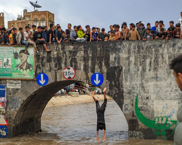 Jovens observam homem saltando de uma ponte na capital do Iêmen, Sanaa, 3 de agosto de 2021 - Sputnik Brasil