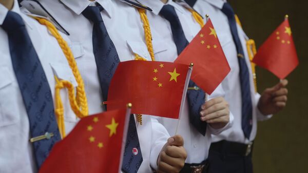 Os alunos seguram as bandeiras nacionais chinesas durante uma cerimônia de hasteamento da bandeira para marcar o 24º aniversário da transferência de Hong Kong para a China, 1º de julho de 2021 - Sputnik Brasil