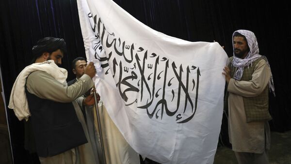 Membros do Talibã organizam uma bandeira do movimento, antes de uma coletiva de imprensa do porta-voz do Taleban Zabihullah Mujahid, no Government Media Information Center, em Cabul, Afeganistão, 17 de agosto de 2021 - Sputnik Brasil