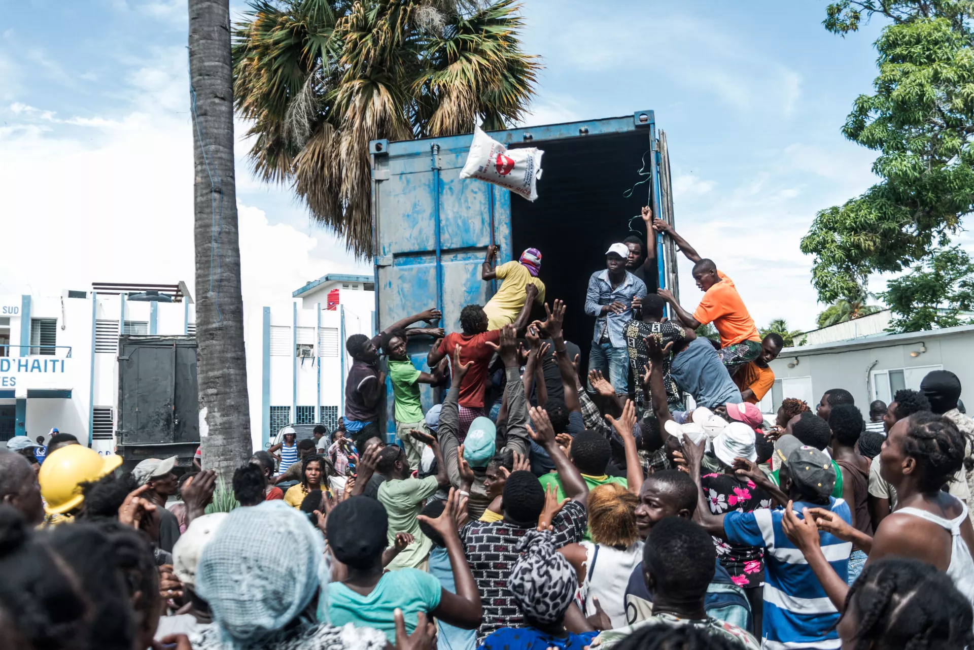 Homem joga saco de arroz para multidão durante distribuição de alimentos e água entre vítimas do terremoto em Les Cayes, Haiti Homem joga saco de arroz para multidão durante distribuição de alimentos e água entre vítimas do terremoto em Les Cayes, Haiti - Sputnik Brasil, 1920, 09.11.2021