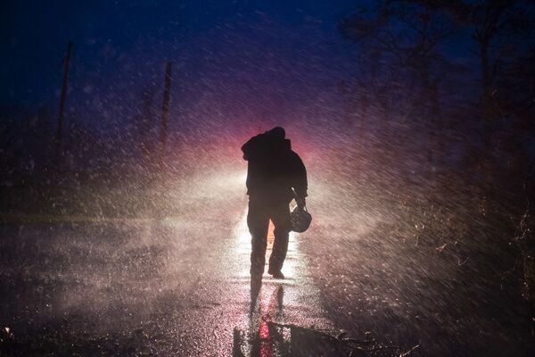 Chefe de bombeiros caminha em chuva pesada enquanto os bombeiros cortam árvores na estrada em Bourg, Louisiana, durante o furacão Ida, 29 de agosto de 2021 - Sputnik Brasil