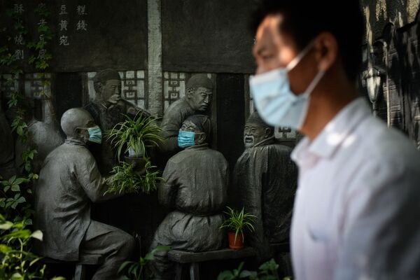 Homem passa por escultura com máscaras perto de um restaurante em Pequim, China. - Sputnik Brasil