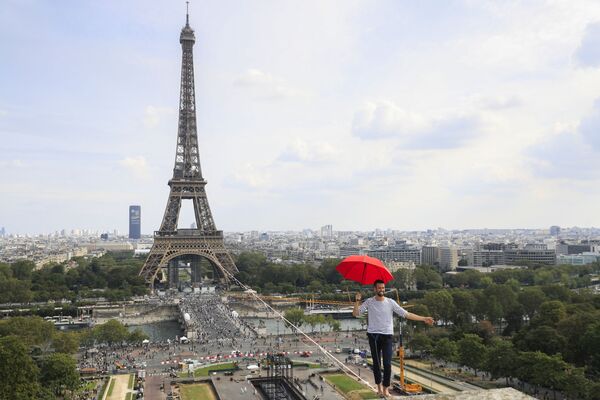 O francês Nathan Paulin segura um guarda-chuva enquanto caminha sobre uma corda a 70 metros de altura, estendida por 670 metros entre a Torre Eiffel e o Teatro Nacional de Chaillot, em Paris, na França, em 19 de setembro de 2021. - Sputnik Brasil