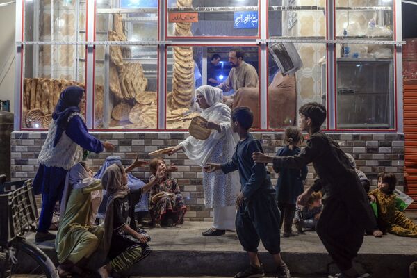 Mulher oferece pão a jovens pobres em Cabul, no Afeganistão, em 19 de setembro de 2021. - Sputnik Brasil