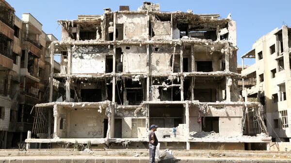 Homem passa por prédio danificado em Homs, Síria, 3 de outubro de 2021 - Sputnik Brasil