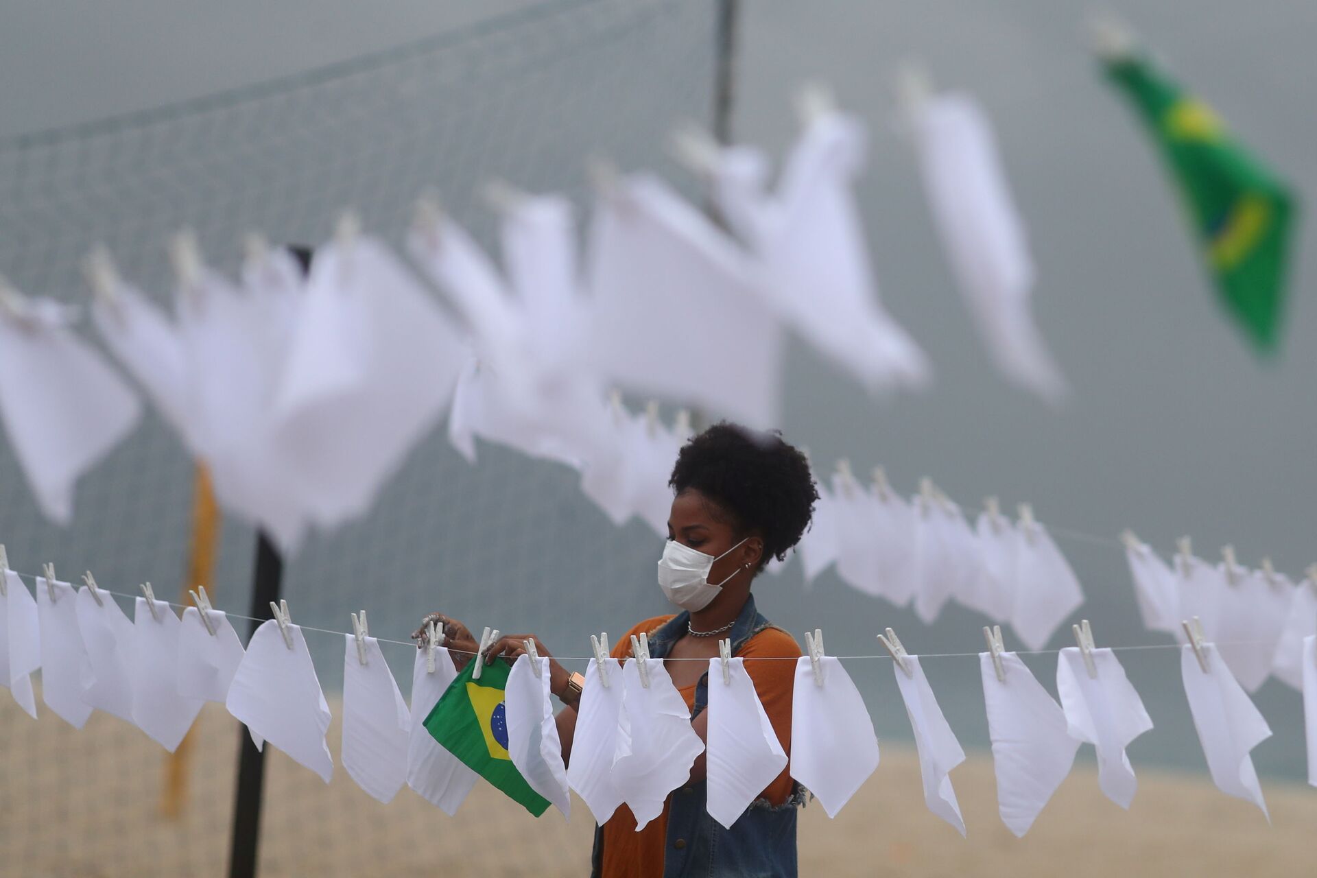 Membro de organização sem fins lucrativos Rio de Paz, estende lenços brancos junto a bandeira do Brasil, simbolizando a mais de 600 mil mortes fruto da COVID-19 no país, no Rio de Janeiro, no Brasil, em 8 de outubro de 2021 - Sputnik Brasil, 1920, 23.12.2021