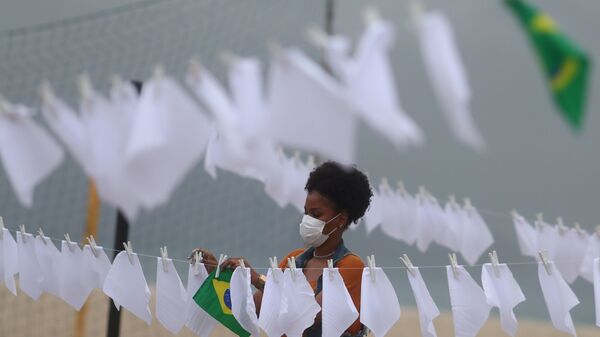 Membro de organização sem fins lucrativos Rio de Paz, estende lenços brancos junto a bandeira do Brasil, simbolizando a mais de 600 mil mortes fruto da COVID-19 no país, no Rio de Janeiro, no Brasil, em 8 de outubro de 2021 - Sputnik Brasil
