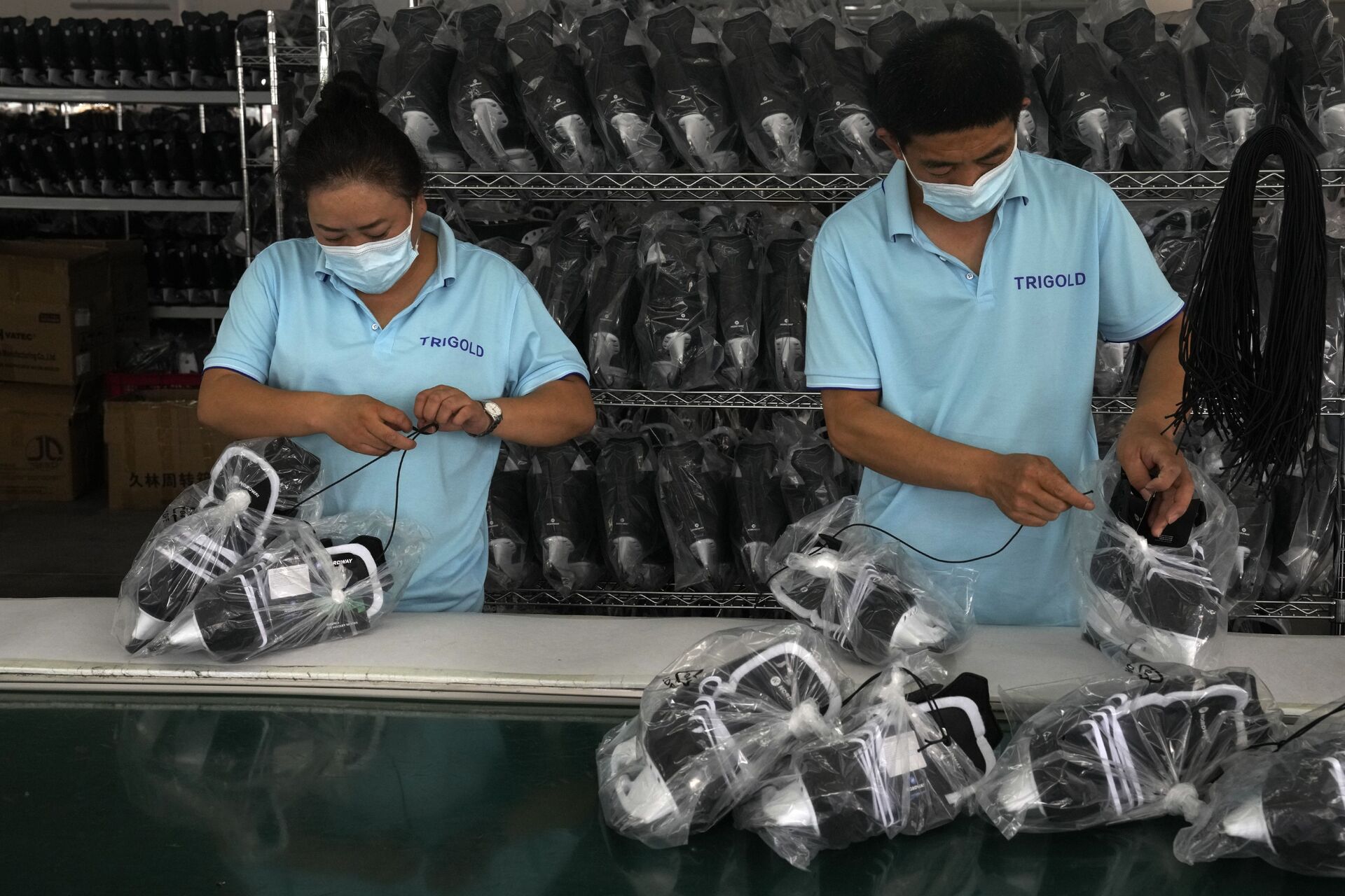 Trabalhadores embalam calçados de patinação no gelo em uma fábrica no parque industrial de equipamentos esportivos de gelo e neve em Zhangjiakou, na província de Hebei, China, 15 de julho de 2021 - Sputnik Brasil, 1920, 09.11.2021