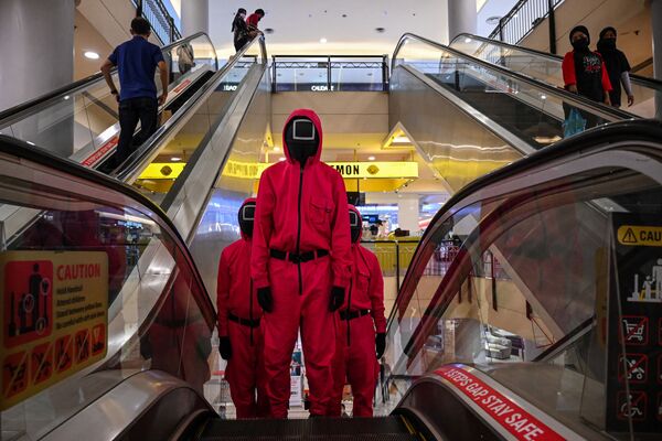 Cosplayers vestidos com roupas da série da Netflix Round 6 em escada rolante em um centro comercial em Kuala Lumpur, Malásia. - Sputnik Brasil