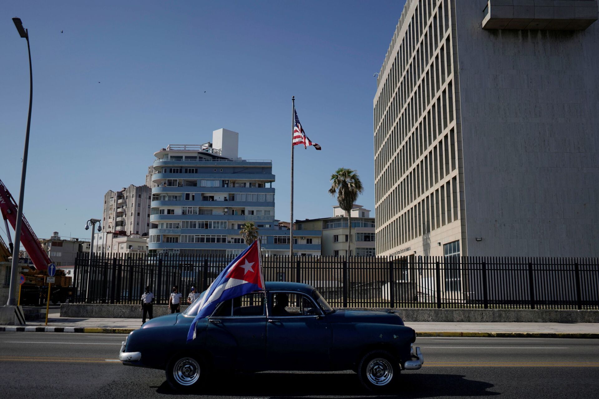 Carro antigo passa pela embaixada dos EUA carregando uma bandeira cubana durante carreata de protesto contra o embargo contra Cuba pelos EUA, Havana, 28 de março de 2021 - Sputnik Brasil, 1920, 09.11.2021
