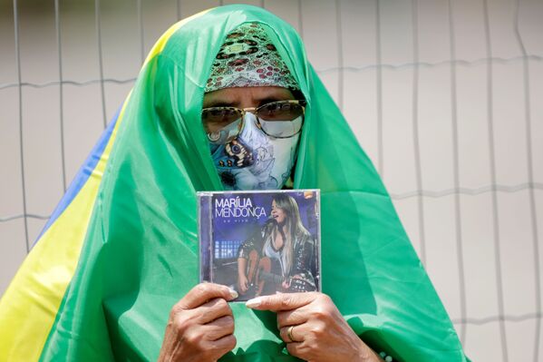 Fã da cantora Marília Mendonça segura CD enquanto espera por seu velório no centro esportivo Goiânia Arena, estado de Goiás, Goiânia, Brasil, 6 de novembro de 2021. - Sputnik Brasil