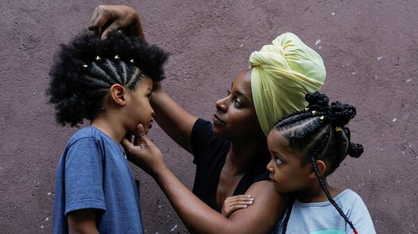 A trançadora de cabelo Tati Braz, 36, arruma o cabelo do filho, Akin, 7, depois de trançar um antigo padrão da realeza africana enquanto se senta com sua filha Asantewa, de 4, também trançada por ela, em São Paulo, Brasil, 8 de novembro de 2021 - Sputnik Brasil