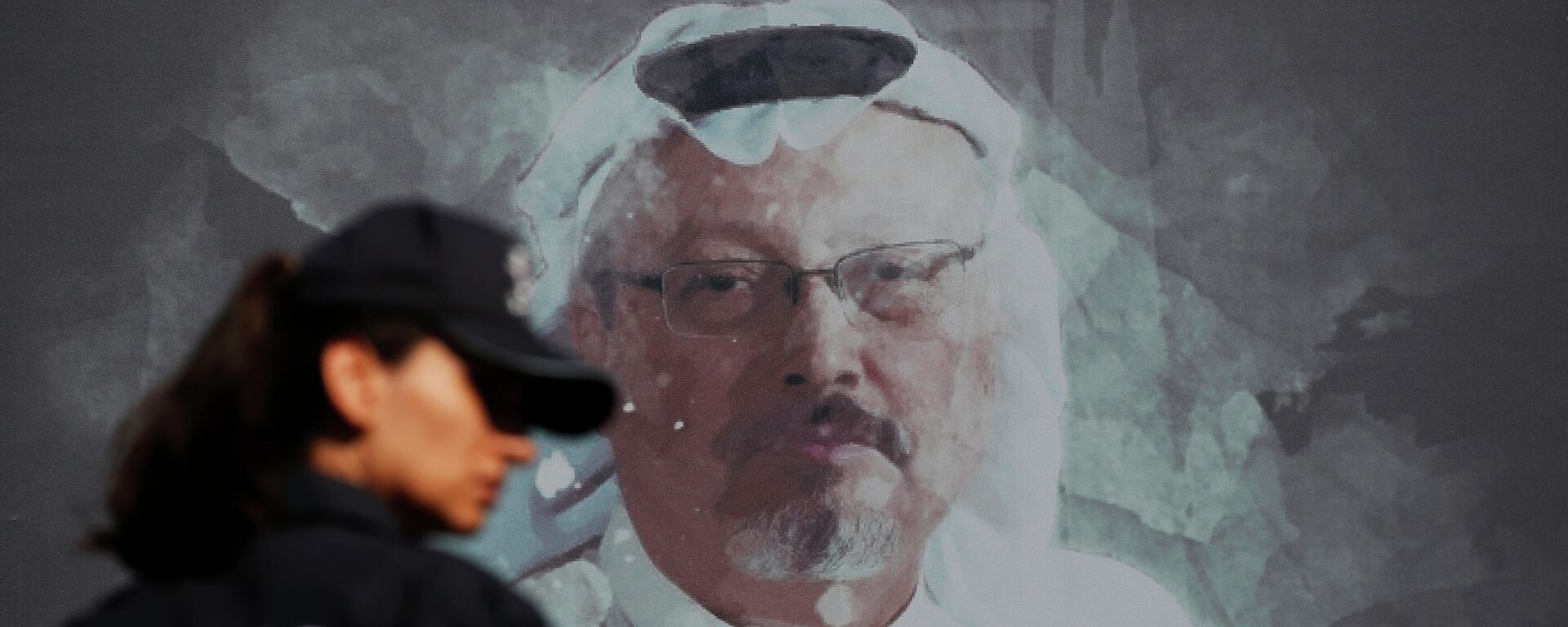 Um policial turco passa por uma foto do jornalista saudita Jamal Khashoggi antes de uma cerimônia, perto do consulado da Arábia Saudita em Istambul, marcando o aniversário de um ano de sua morte, no dia 2 de outubro de 2019 - Sputnik Brasil, 1920, 23.11.2021