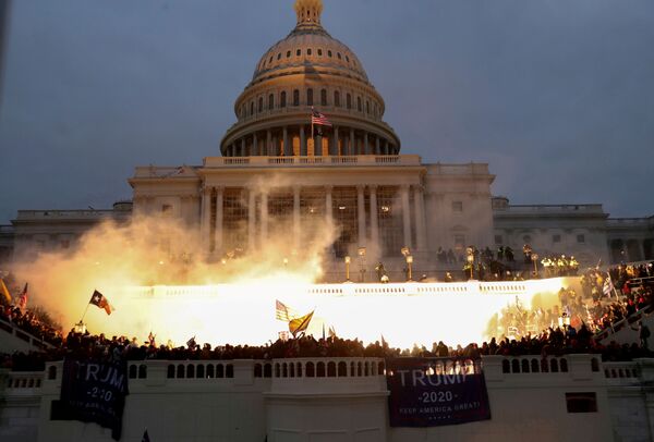 Explosão causada por uma munição da polícia é vista enquanto apoiadores do presidente dos EUA, Donald Trump, reúnem-se em frente ao Capitólio, em Washington, 6 de janeiro de 2021. - Sputnik Brasil