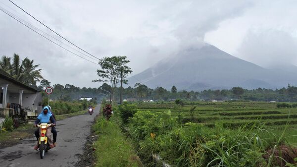 Os motoristas viajam em uma estrada de aldeia enquanto o Monte Semeru é visto expelindo fumaça vulcânica em Lumajang, Java Oriental, Indonésia, 17 de janeiro de 2021 - Sputnik Brasil