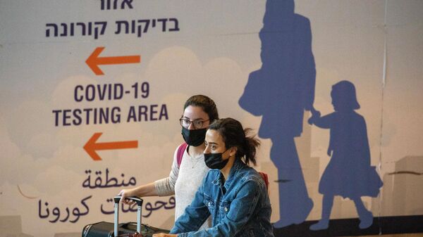 Em Tel Aviv, viajantes usando máscaras contra a COVID-19 chegam ao aeroporto Ben Gurion, em 28 de novembro de 2021 - Sputnik Brasil