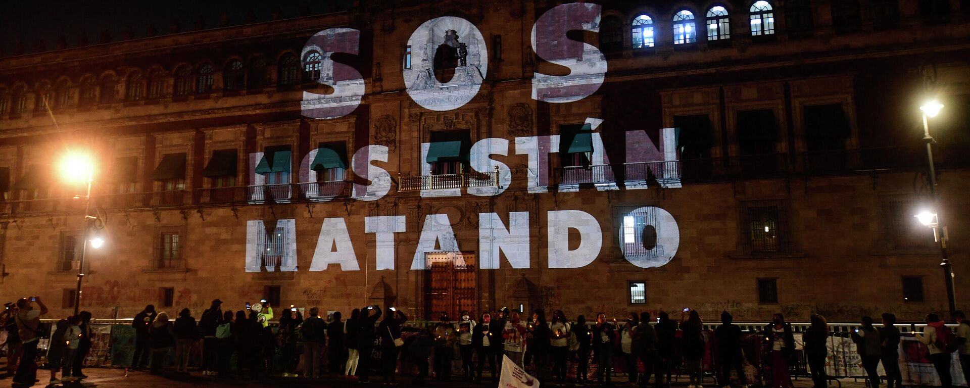 As palavras SOS, eles estão nos matando são projetadas no Palácio Nacional. Pessoas se reúnem durante uma vigília com parentes de vítimas de feminicídio e desaparecimentos forçados na Cidade do México. México, 28 de março de 2021 - Sputnik Brasil, 1920, 24.01.2025