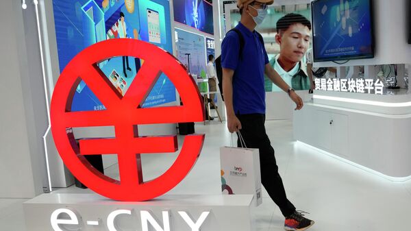 Um visitante passa por um logotipo do e-CNY, uma versão digital do Yuan chinês, exibido durante uma feira comercial em Pequim, China, 5 de setembro de 2021 - Sputnik Brasil