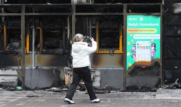Mulher filma prédio queimado durante violentos protestos em massa contra a subida dos preços do combustível, Almaty, Cazaquistão, 9 de janeiro de 2022 - Sputnik Brasil