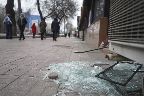 Pessoas passam ao lado de loja com vidros partidos durante violentos protestos em massa em Almaty, Cazaquistão, 10 de janeiro de 2022 - Sputnik Brasil