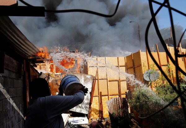 Homem joga água para ajudar a combater incêndio no bairro de baixa renda de Laguna Verde, Iquique, Chile, 10 de janeiro de 2022 - Sputnik Brasil