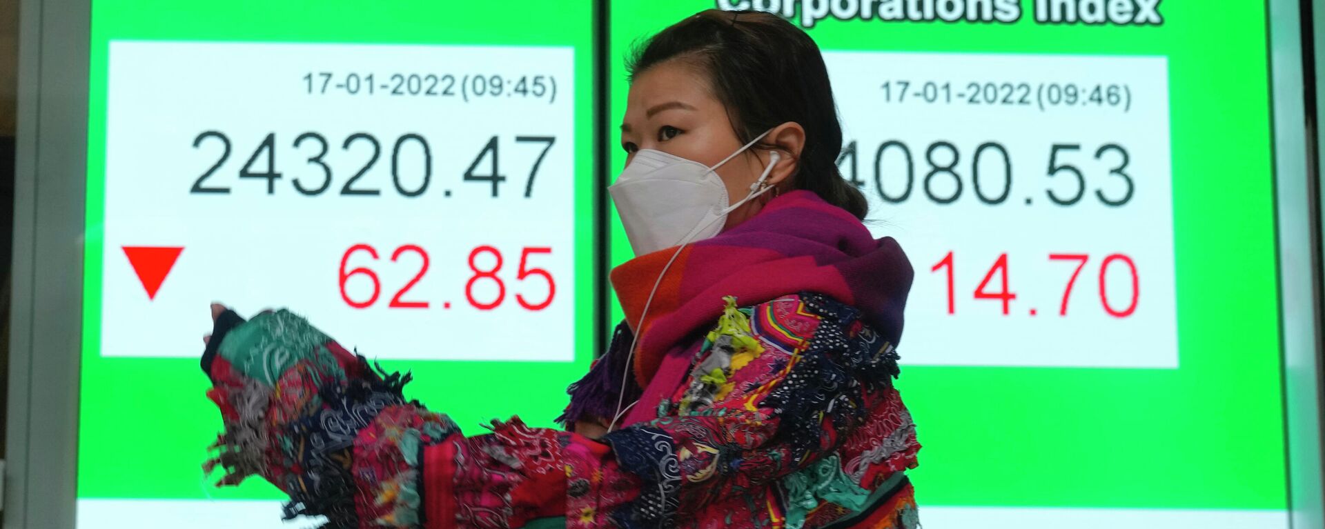 Uma mulher usando uma máscara facial passa pelo quadro eletrônico de um banco mostrando o índice de ações de Hong Kong em Hong Kong, 17 de janeiro de 2022 - Sputnik Brasil, 1920, 18.01.2022