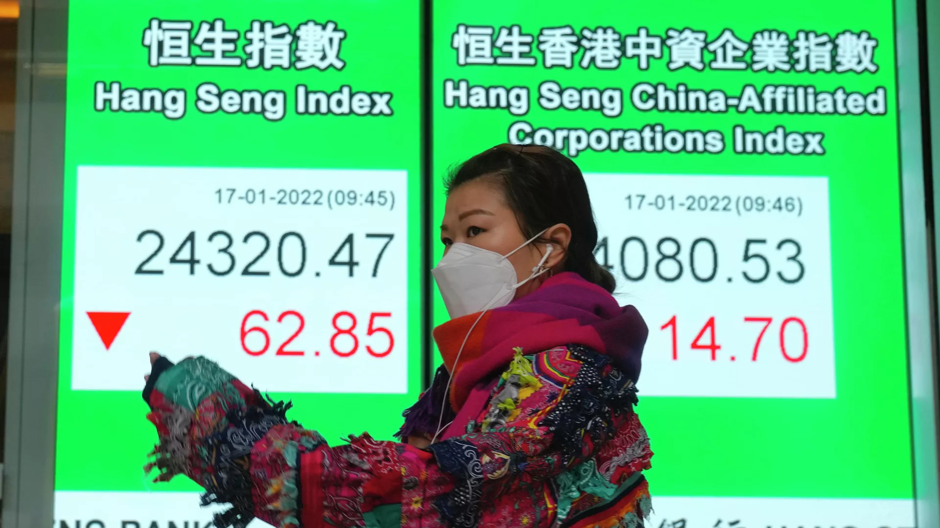 Uma mulher usando uma máscara facial passa pelo quadro eletrônico de um banco mostrando o índice de ações de Hong Kong em Hong Kong, 17 de janeiro de 2022 Uma mulher usando uma máscara facial passa pelo quadro eletrônico de um banco mostrando o índice de ações de Hong Kong em Hong Kong, 17 de janeiro de 2022 - Sputnik Brasil, 1920, 18.01.2022