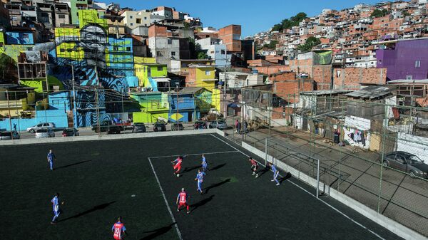 Residentes jogando futebol, com a imagem do jogador de futebol Gabriel Jesus ao fundo, pintado nas paredes das casas do bairro de Perus, São Paulo, Brasil - Sputnik Brasil