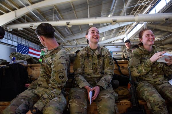 Especialista Tommy Love, centro, e especialista Caitlyn Bickler, à direita, riem com sua pronúncia do russo ao estudar guia de idiomas enquanto esperam com outros soldados da 82ª Divisão Aerotransportada para embarcar para a Polônia, em Fort Bragg, Carolina do Norte, EUA, 14 de fevereiro de 2022. - Sputnik Brasil