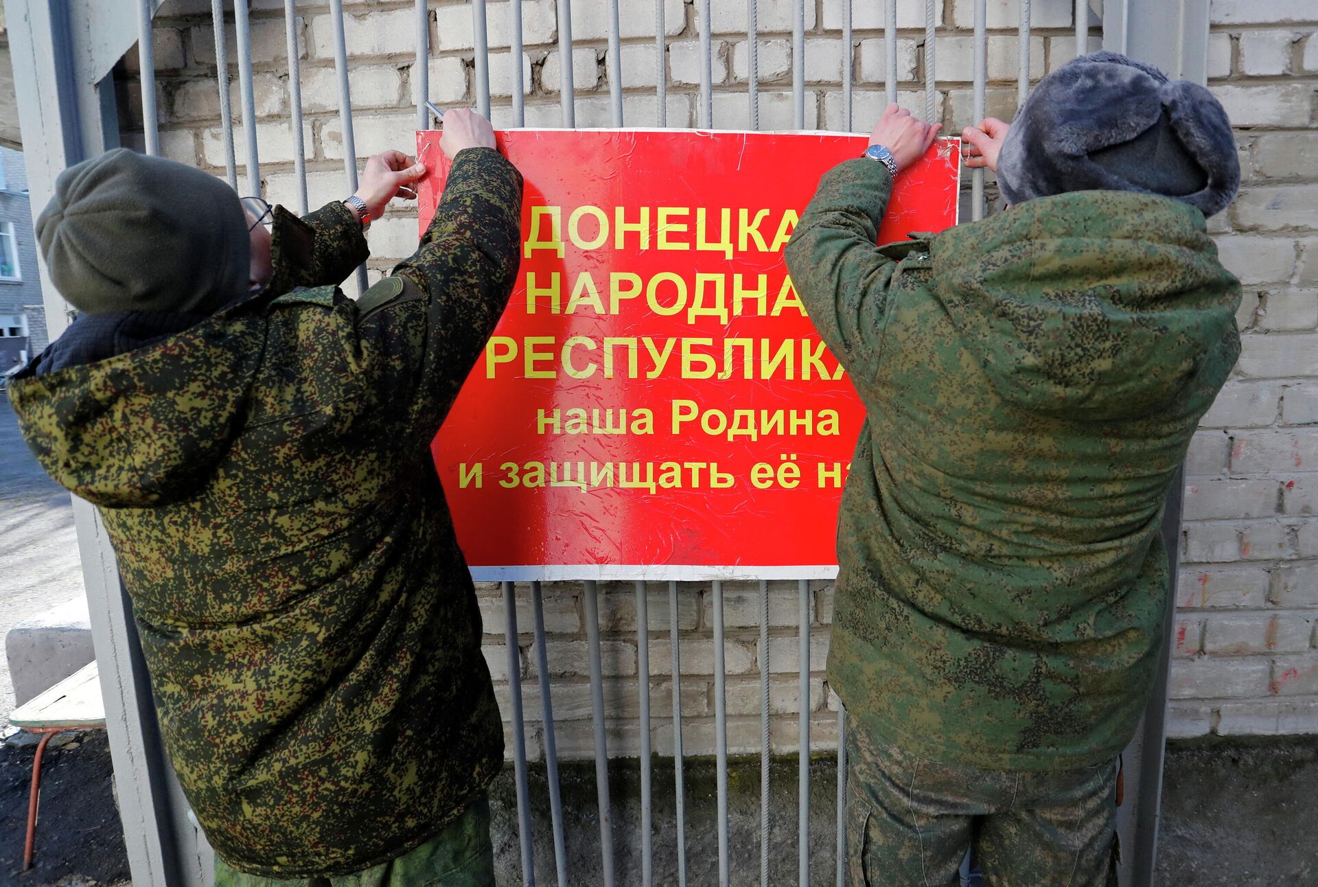 Militares da autoproclamada República Popular de Donetsk pendurando faixa nas portas de uma escola que diz: A República Popular de Donetsk é nossa pátria e nós devemos defendê-la!, Donetsk, 19 de fevereiro de 2022 - Sputnik Brasil, 1920, 24.02.2022