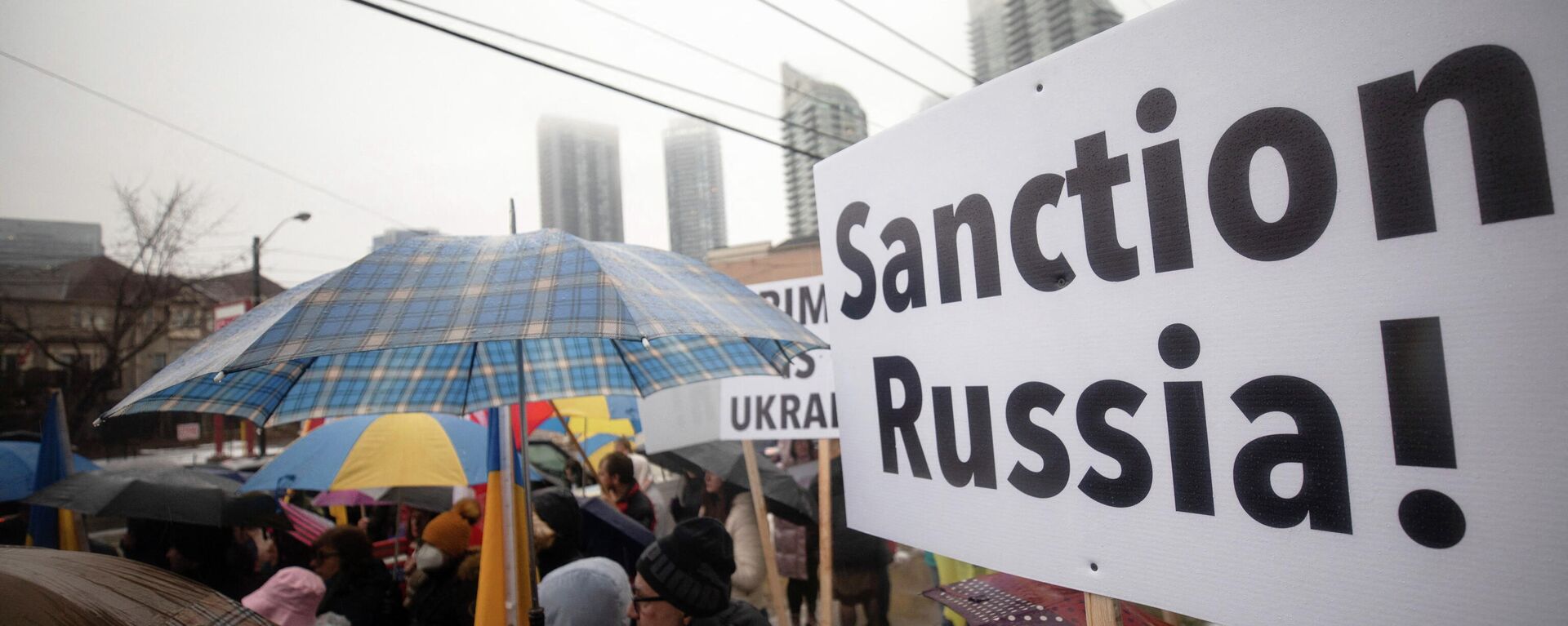 Manifestante segura cartaz que diz Sancione a Rússia! durante ato ao lado do Consulado ucraniano em Toronto, Canadá, 22 de fevereiro de 2022. - Sputnik Brasil, 1920, 24.03.2022