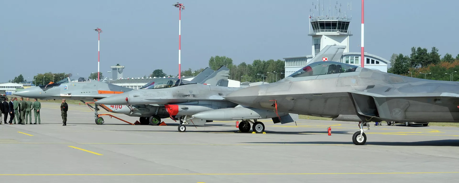 Autoridades passam por caças estacionados no pátio, um Mig-29 da Força Aérea Polonesa, à esquerda, um F-16 da Força Aérea Polonesa, ao centro e um F-22 Raptor dos EUA em uma base militar em Lask, Polônia, segunda-feira, 31 de agosto de 2015 - Sputnik Brasil, 1920, 13.08.2024