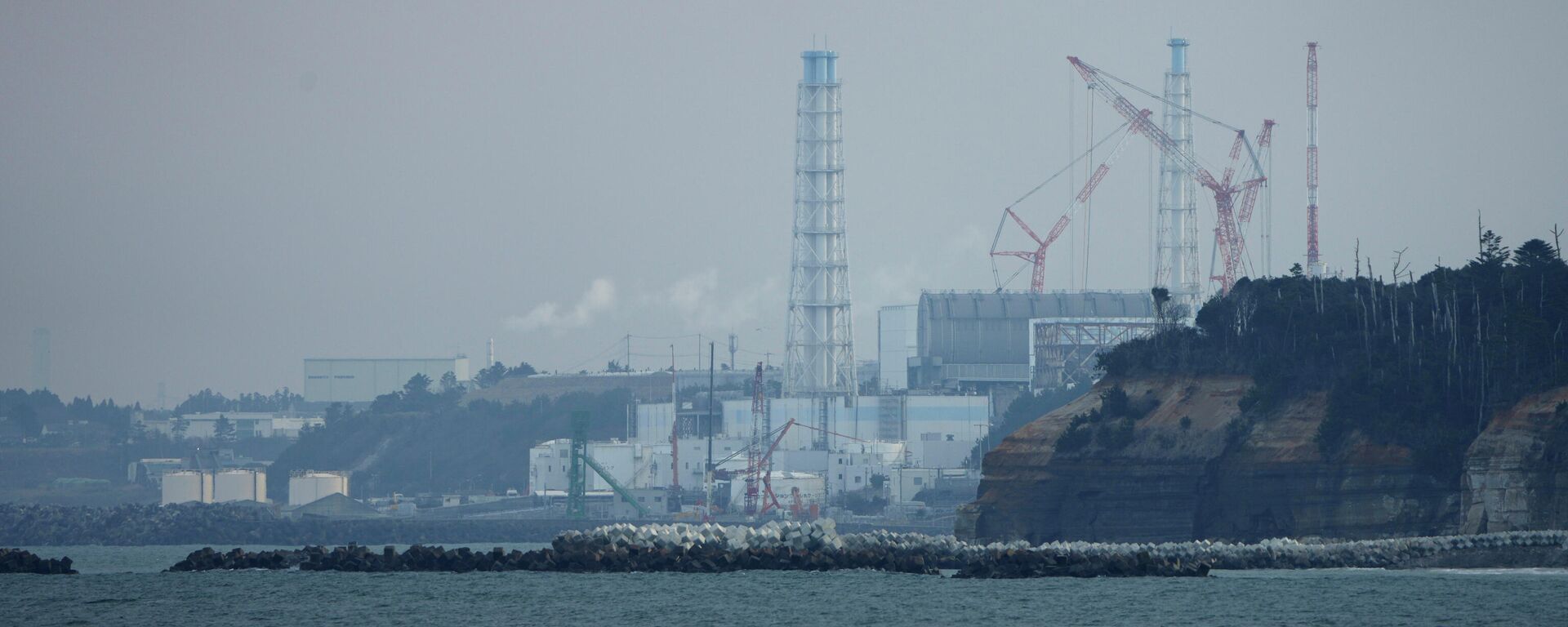 A usina nuclear de Fukushima Daiichi fica nas cidades costeiras de Okuma e Futaba, vista do porto de pesca de Ukedo na cidade de Namie, nordeste do Japão, quarta-feira, 2 de março de 2022 - Sputnik Brasil, 1920, 23.07.2022