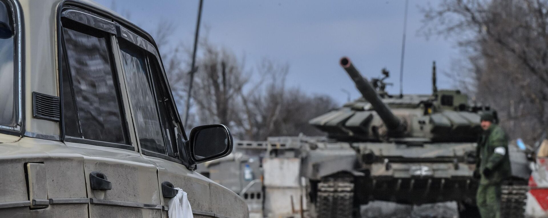 Em Mariupol, na República Popular de Donetsk (RPD), um carro com residentes locais é visto deixando a cidade com um tanque militar ao fundo, em 24 de fevereiro de 2022 - Sputnik Brasil, 1920, 21.03.2022