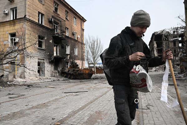 Morador da cidade fuma junto de prédio residencial destruído em Mariupol - Sputnik Brasil