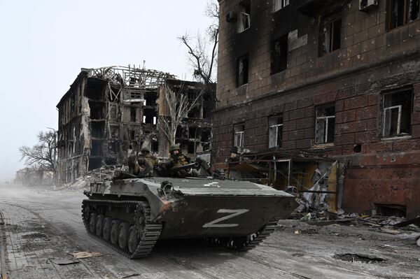 Carro de combate da infantaria BMP-1 das forças da República Popular de Donetsk junto de prédio residencial destruído em Mariupol - Sputnik Brasil