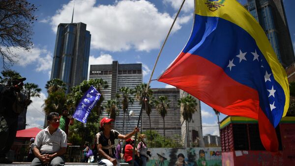 Apoiador do governo hasteia bandeira venezuelana durante o 20º aniversário do golpe de Estado que temporariamente removeu o então presidente do país, Hugo Chávez. Caracas, Venezuela, 13 de abril de 2022 - Sputnik Brasil