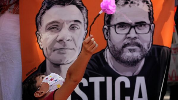 Criança segura flor diante de imagem de Dom Phillips e Bruno Pereira, em protesto em Brasília pelo duplo homicídio ocorrido em 5 de junho, em 19 de junho de 2022 - Sputnik Brasil