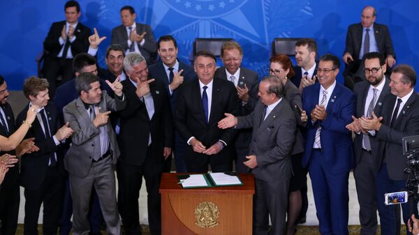 O presidente brasileiro, Jair Bolsonaro (PL), acompanhado de deputados favoráveis a projetos de flexibilização do controle de armas, durante assinatura de decreto presidencial que flexibiliza regras para colecionadores, atiradores desportivos e caçadores (CACs), em Brasília, em 7 de maio de 2019 - Sputnik Brasil