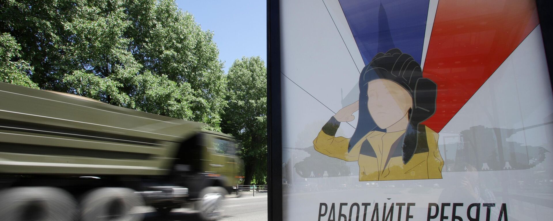 Veículo militar passa ao lado de um cartaz com a imagem do menino Alyosha em uma parada de transporte público em Nalchik, na região russa de Belgorod, 31 de maio de 2022 - Sputnik Brasil, 1920, 02.07.2022