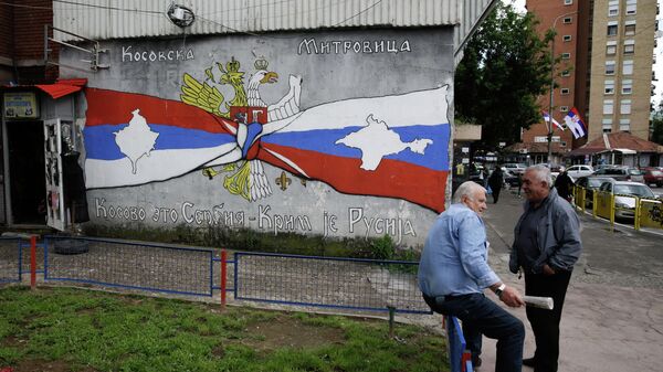 Pessoas descansam ao lado de grafite com os escritos Kosovo é Sérvia, Crimeia é Rússia, em Kosovska Mitrovica, Sérvia, 28 de maio de 2019 - Sputnik Brasil