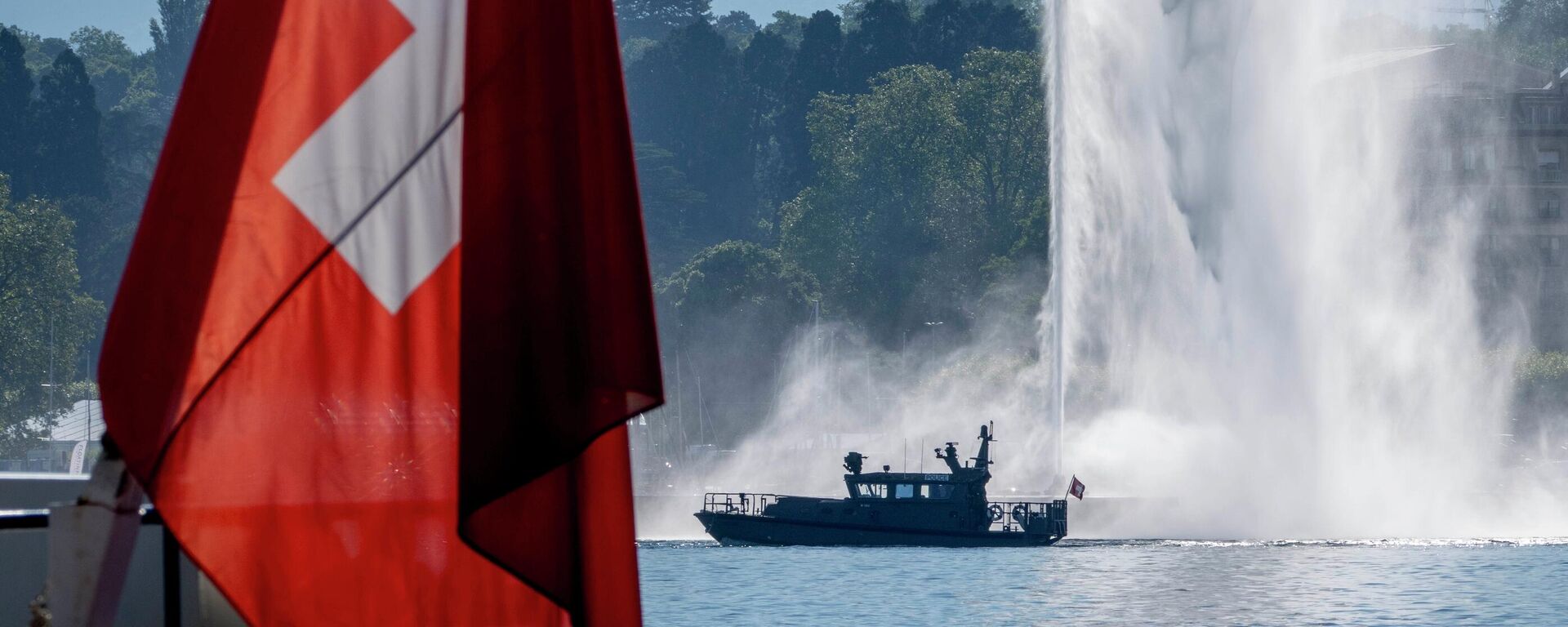 Um barco da polícia passa por uma bandeira suíça e uma fonte no Lago Genebra, em Genebra, Suíça, terça-feira, 15 de junho de 2021 - Sputnik Brasil, 1920, 04.08.2022