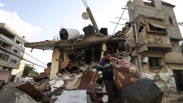 Homem carrega seus pertences após destruição promovida pro Israel em Gaza - Sputnik Brasil